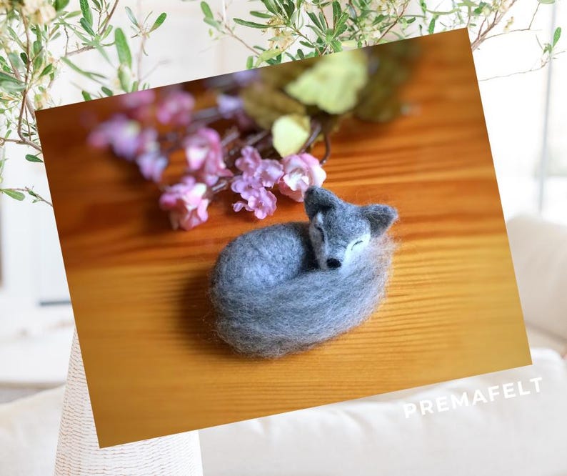 In the picture, a fluffy wool toy little wolf is lying curled up