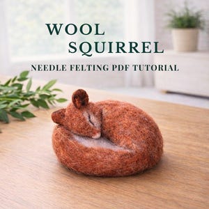 May include: A curled-up, needle-felted squirrel in shades of brown and tan rests on a wooden surface. The text "WOOL SQUIRREL NEEDLE FELTING PDF TUTORIAL" is displayed above the squirrel. A small plant in a pot is in the background.