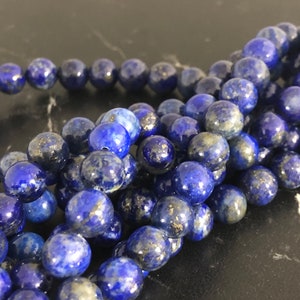 Peut inclure: Un brin de perles de lapis-lazuli bleu foncé avec des paillettes de pyrite dorée. Les perles sont rondes et lisses, et elles sont enfilées sur un fil transparent.
