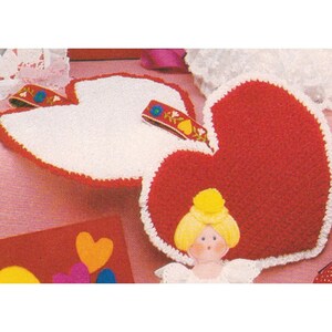 May include: Two heart-shaped crochet items, one red and one white, with white trim. Decorative embellishments include a small doll and colorful ribbon. The items are likely handmade and suitable for Valentine's Day or other special occasions.