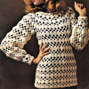 May include: A white crocheted sweater with a geometric pattern. The sweater has long sleeves and a round neckline.