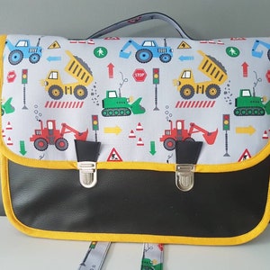 Cartable maternelle (34cm x24 cm), simili cuir noir  et tissu engins avec  porte- étiquette, bretelles réglables.
