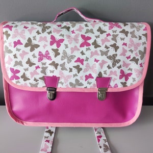 Cartable maternelle (34cm x24 cm), simili cuir rose et tissu papillons avec  porte- étiquette, bretelles réglables.