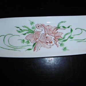 May include: A white rectangular ceramic serving dish with a hand-painted design of two orange goldfish swimming among green aquatic plants.