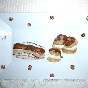 Petit plat rectangulaire en porcelaine peinte main décoré d'un éclair et de profiteroles au chocolat.