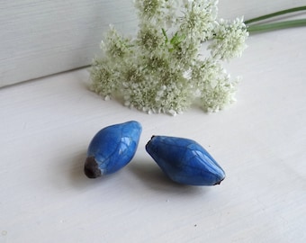 May include: Two blue ceramic beads with a crackled glaze finish. The beads are oval shaped and have a dark blue colour.