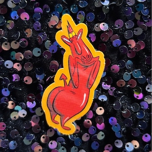 May include: A red cartoon devil with a yellow crown and a tail, standing with its arms crossed. The devil is on a yellow background.