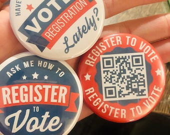Peut inclure: Trois boutons ronds de couleur rouge, blanc et bleu. Le bouton du haut dit "Avez-vous vérifié votre inscription électorale récemment ?" Le bouton de gauche dit "Demandez-moi comment vous inscrire pour voter." Le bouton de droite a un code QR et dit "Inscrivez-vous pour voter."