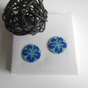 May include: Two round blue and white enamel flower charms with a blue hibiscus flower design.