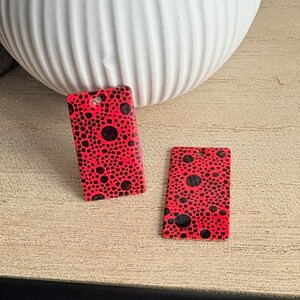 May include: Two rectangular pendants featuring a vibrant neon red base color with a dense, irregular pattern of black circular spots of varying sizes. Each pendant has a small circular hole at the top center for attachment, creating a bold look.