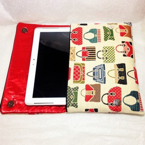 May include: A red and cream colored tablet case with a zipper closure. The case is decorated with a pattern of colorful handbags. The tablet is visible inside the case.