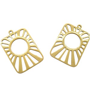 Peut inclure: Deux pendentifs rectangulaires dorés avec un motif de soleil. Chaque pendentif présente une ouverture circulaire centrale entourée de lignes rayonnantes et une petite boucle en haut pour l'attache. Les pendentifs sont sur fond blanc.