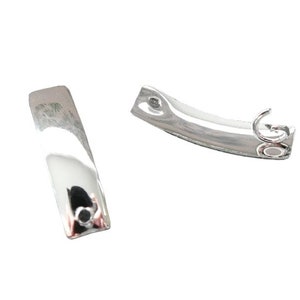 Peut inclure: Deux fermoirs de boucles d'oreilles en métal argenté. Un fermoir est une barre droite avec un petit trou en haut. L'autre fermoir est une barre incurvée avec un crochet à l'extrémité.