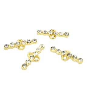 May include: Four gold-toned metal T-bar clasps with clear rhinestone accents.