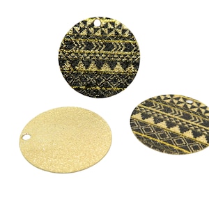 May include: Three round, gold glitter ornaments with black geometric patterns. Two of the ornaments have a black and gold geometric pattern, and one is solid gold glitter.