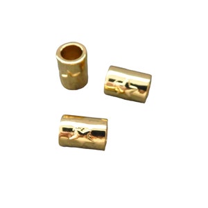 May include: Three gold-colored metal beads with a star design. The beads are cylindrical in shape and have a smooth, shiny finish.
