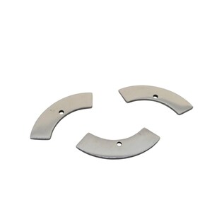 May include: Three silver-colored, crescent-shaped metal pieces with a small hole in each. The pieces are arranged on a white background. The objects appear to be components or parts.
