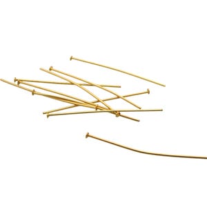 Peut inclure: Un tas d'épingles à tête dorées, utilisées pour la fabrication de bijoux et l'artisanat.