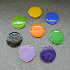 Peut inclure: Huit disques ronds, plats et métalliques avec un trou au centre. Les disques sont peints dans différentes couleurs, notamment le jaune, le vert, le noir, l'orange, le violet et le bleu.