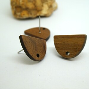 Peut inclure: Trois boucles d'oreilles en bois en forme de demi-cercle avec un trou au centre. Les boucles d'oreilles sont de couleur brun foncé et ont un grain de bois naturel.