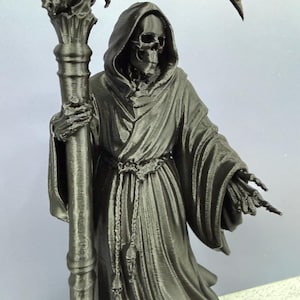 May include: A black 3D printed figurine of a hooded skeleton figure wearing a long robe with a rope belt. The figure holds a tall staff topped with a large scythe blade and a skull detail. The skeleton has an exposed rib cage and bony hands.