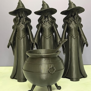 May include: Three dark green witch figurines with pointed hats and long dresses stand behind a cauldron with a spoon. The cauldron has three legs and a ring handle. The figures are detailed and have long flowing hair.