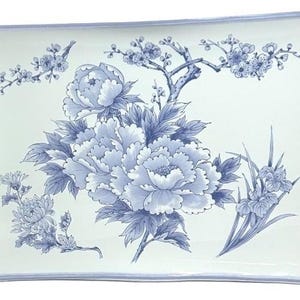 以下が含まれることがあります： 白いベースに青い花柄が描かれた長方形の陶磁器製サービングトレイ。中央に大きな牡丹、枝に小さな花、そして葉のついた茎がデザインされています。トレイの縁は細い青い線で縁取られています。