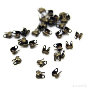 Op de afbeelding: Een stapel kleine, antieke, goudkleurige metalen eindkappen voor het maken van sieraden.