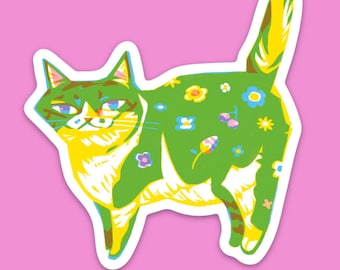 May include: A sticker featuring a stylized cat illustration. The cat is green with yellow and white accents, and adorned with colorful flower designs. The sticker has a white border and is set against a pink background.
