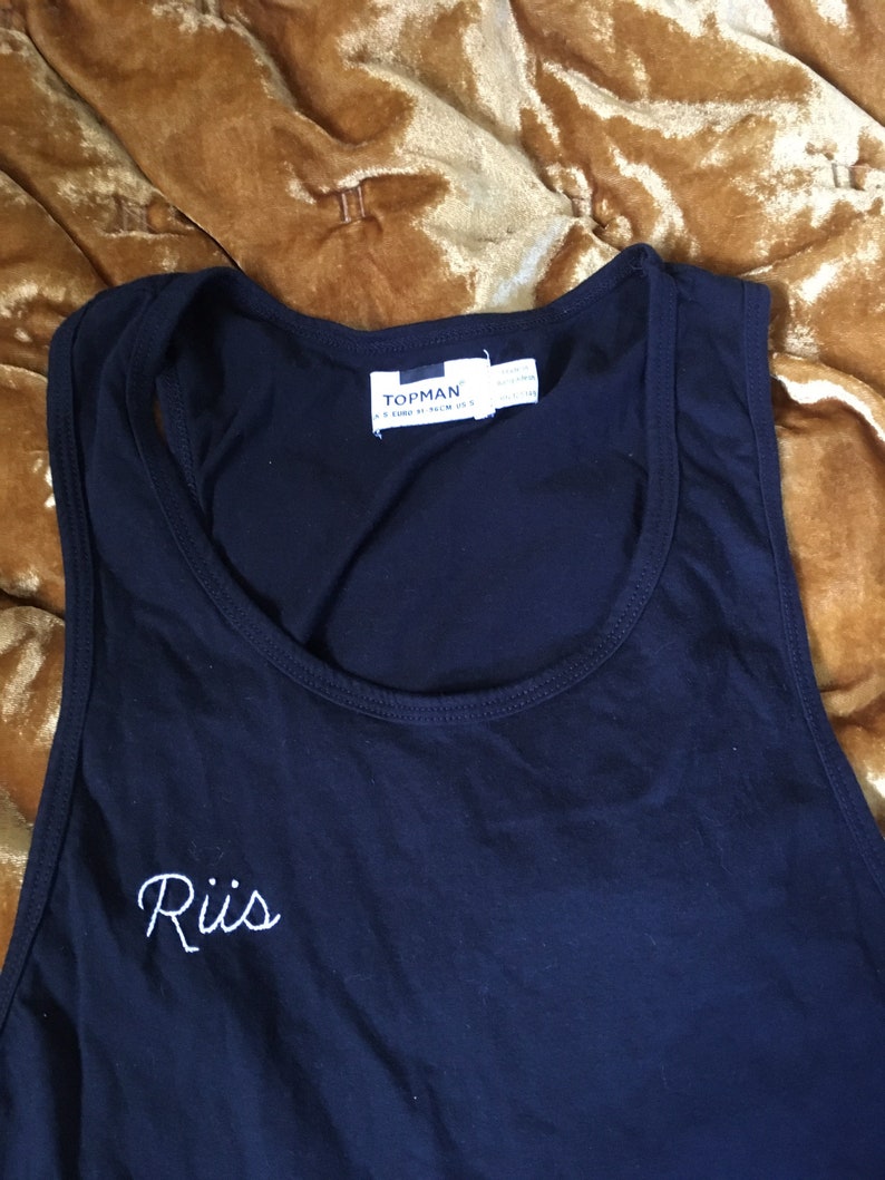 Riis hand embroidered in bright white on an unworn black tank by me Tank is originally from Top Man and is a men\u2019s size small but I\u2019d go b