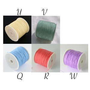 May include: Five spools of thread in different colors: light yellow, light green, light blue, light pink, and light purple. The spools are labeled with the letters U, V, Q, R, and W.