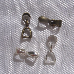 Peut inclure: Quatre fermoirs de bijoux en métal, deux argentés et deux bronze. Les fermoirs sont conçus pour tenir un pendentif ou un charme.