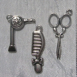 Puede incluir: Encantos de metal plateado que representan un secador de pelo, un peine con un lazo y unas tijeras. Estos abalorios están diseñados para la fabricación de joyas o proyectos de artesanía. Los abalorios miden aproximadamente 2,5 cm de largo.