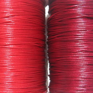 May include: Two cylindrical spools of cord are positioned side by side. The spool on the left features a bright, vibrant red cord, while the spool on the right is wrapped in a slightly darker, deeper shade of red cord with a smooth, glossy finish.