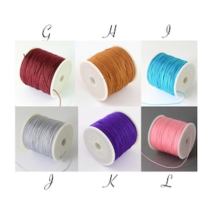 May include: Six spools of colorful cord in various shades: burgundy, tan, turquoise, silver, purple, and pink. Each spool is wound around a white plastic core. The letters G, H, I, J, K, and L are written above each spool.