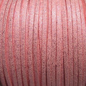 May include: A close-up of a spool of pink leather cord with a glittery finish.