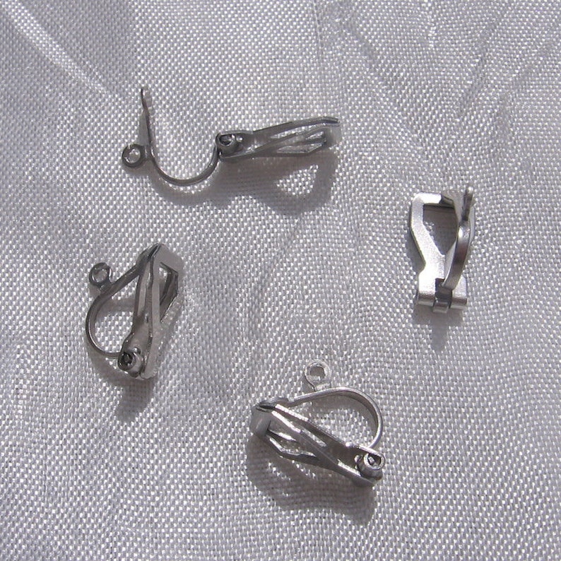 May include: Four silver-toned earring clips with a spring-loaded closure. The clips are designed to hold earrings in place without piercing the ear.