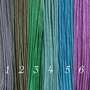 May include: Six spools of embroidery floss in different colors: gray, dark green, green, light blue, blue, and purple.