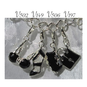 May include: Four silver charm bracelets with black enamel accents. The charms include a high heel shoe, a handbag, and two different styles of purses. The charms are attached to a silver chain.