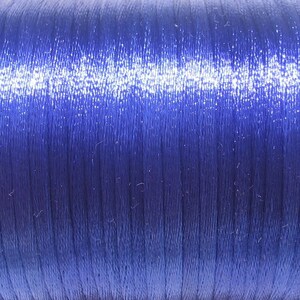 Puede incluir: Primer plano de un carrete de hilo azul oscuro. El hilo tiene un ligero brillo y est&aacute; enrollado apretado.