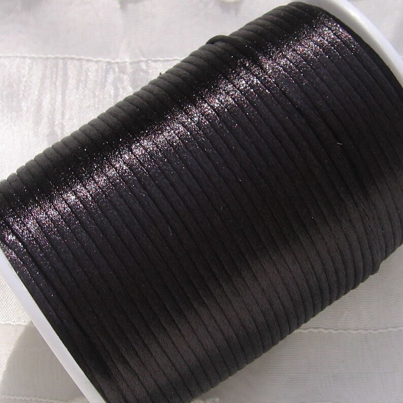 Puede incluir: Una bobina de cord&oacute;n de sat&eacute;n negro, un tipo de cord&oacute;n delgado, plano y liso que se utiliza a menudo para la elaboraci&oacute;n de joyas y manualidades.