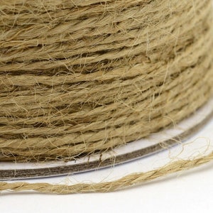May include: Close-up of a spool of natural brown twine. The twine is made of natural fibers and has a rough texture.