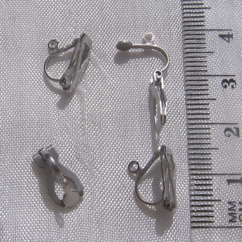 May include: Four silver-toned clip-on earring backs. The backs are designed to be used with earrings that have a post.