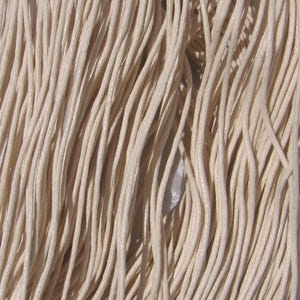 May include: Close-up of a bundle of off-white, waxed cotton cord. The cords are tightly packed together, creating a textured surface. The cords are likely used for jewellery making, crafts, or other DIY projects.