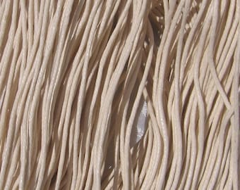May include: Close-up of a bundle of off-white, waxed cotton cord. The cords are tightly packed together, creating a textured surface. The cords are likely used for jewelry making, crafts, or other DIY projects.