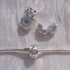 Op de afbeelding: Zilveren armband met bedels met een zilveren hartbedel. De bedel is een spacer bead met een hartontwerp.