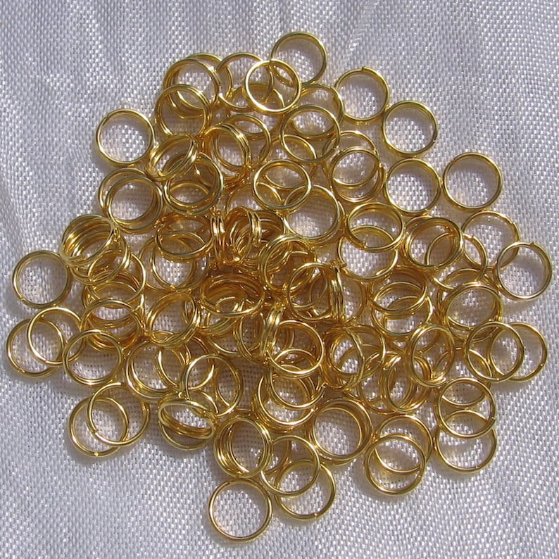 May include: A large pile of gold jump rings. The rings are all the same size and are arranged in a random pattern.