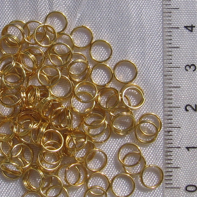May include: A large pile of gold jump rings. The rings are approximately 1/2 inch in diameter.