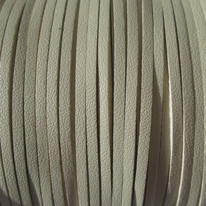 May include: Close-up of a spool of off-white leather cord. The cord is arranged in parallel lines, creating a textured pattern.