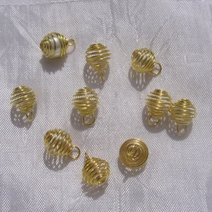 May include: Ten gold wire cage pendants, one of which contains a single white pearl. The cages are all closed and have a small loop at the top for hanging.
